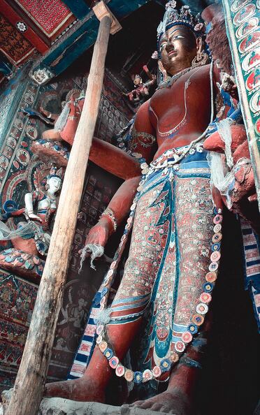 Maitreya is painted red, his face is gilded, and he has four arms. A four-headed Vairocana is depicted in the central point of his five-Buddha crown. The image has a height of 463 cm and its dhoti is decorated with the life of a Buddha (Fig. 1 in Orientations). © Jaroslav Poncar AlchiSTS MMN M JP81.jpg
